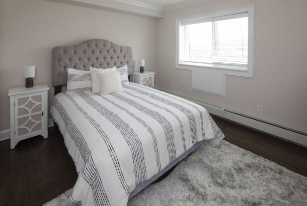 Cadillac Monar A tidy bedroom with a striped bedspread, tufted headboard, two nightstands, and a large window.