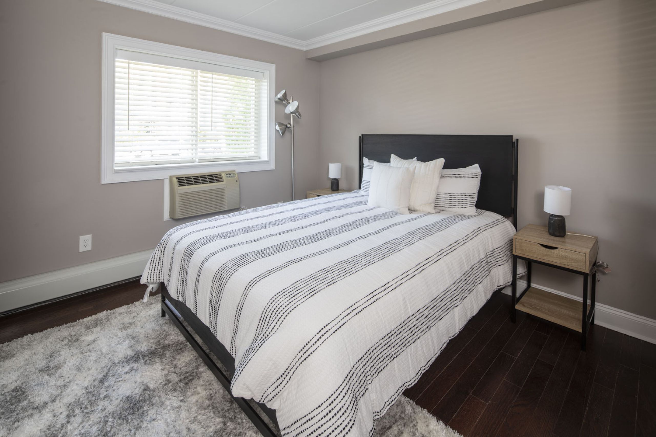 Cadillac Manor A modern apartment building with landscaped gardens and a wooden entrance canopy under a partly cloudy sky.