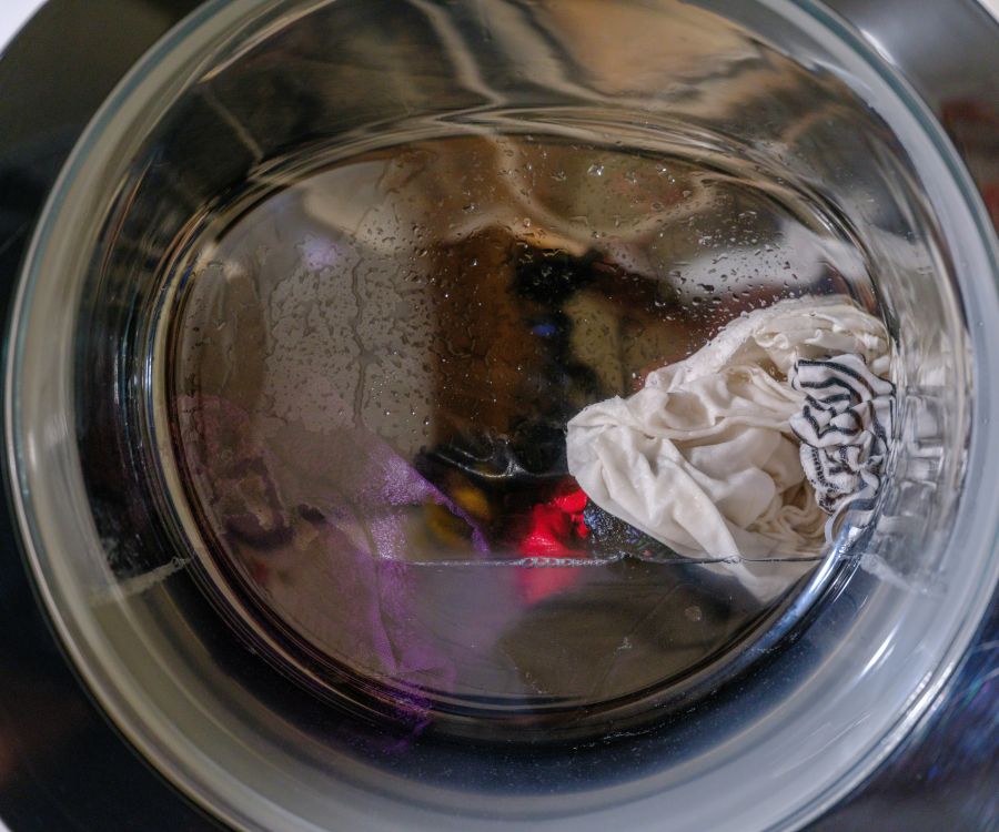 Cadillac Manor A stack of folded white towels with a sprig of yellow flowers on top against a white background.