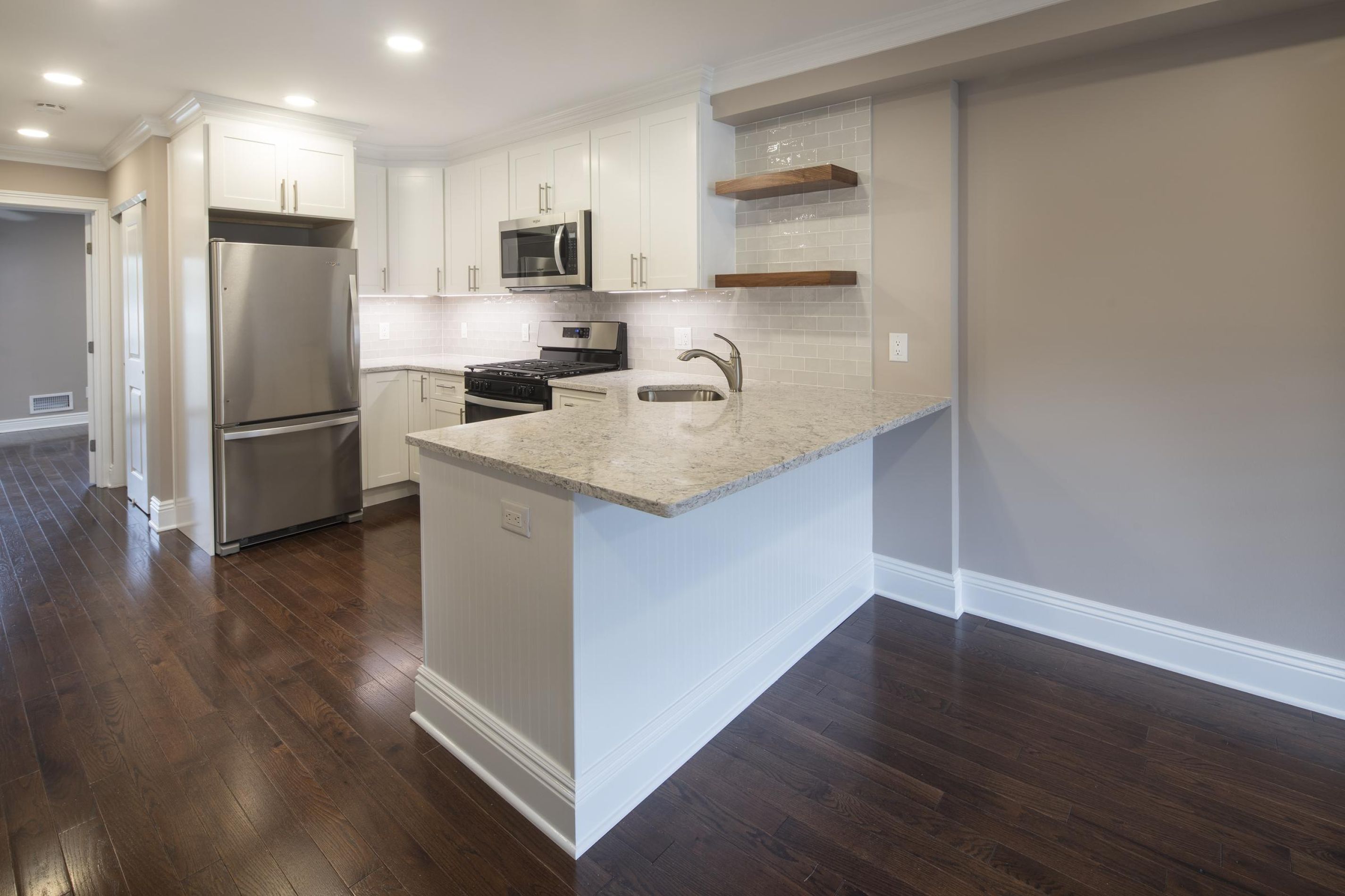 Cambridge Manor Modern kitchen with stainless steel appliances, white cabinets, granite counters, and wood flooring.