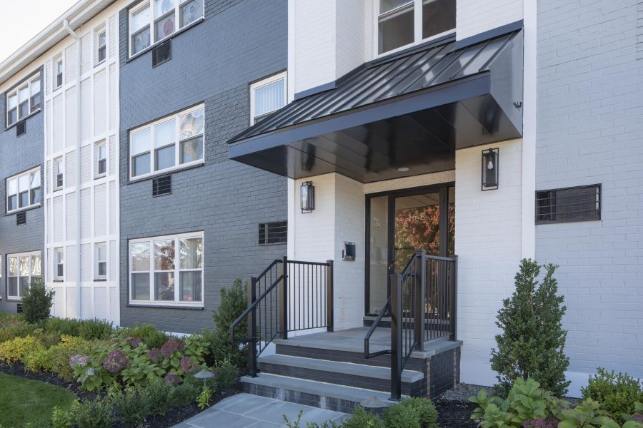 Hickory Manor A modern apartment building with landscaped gardens and a wooden entrance canopy under a partly cloudy sky.