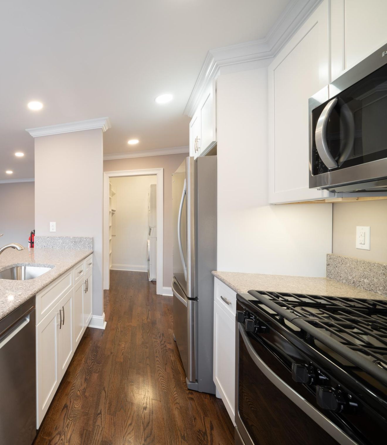 Hickory Manor Modern kitchen with granite countertops, stainless steel appliances, and hardwood floors, brightly lit.
