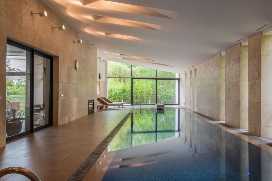 Legion Manor Modern Spacious Indoor Swimming Pool with lounge seating near picture windows looking out to the forest