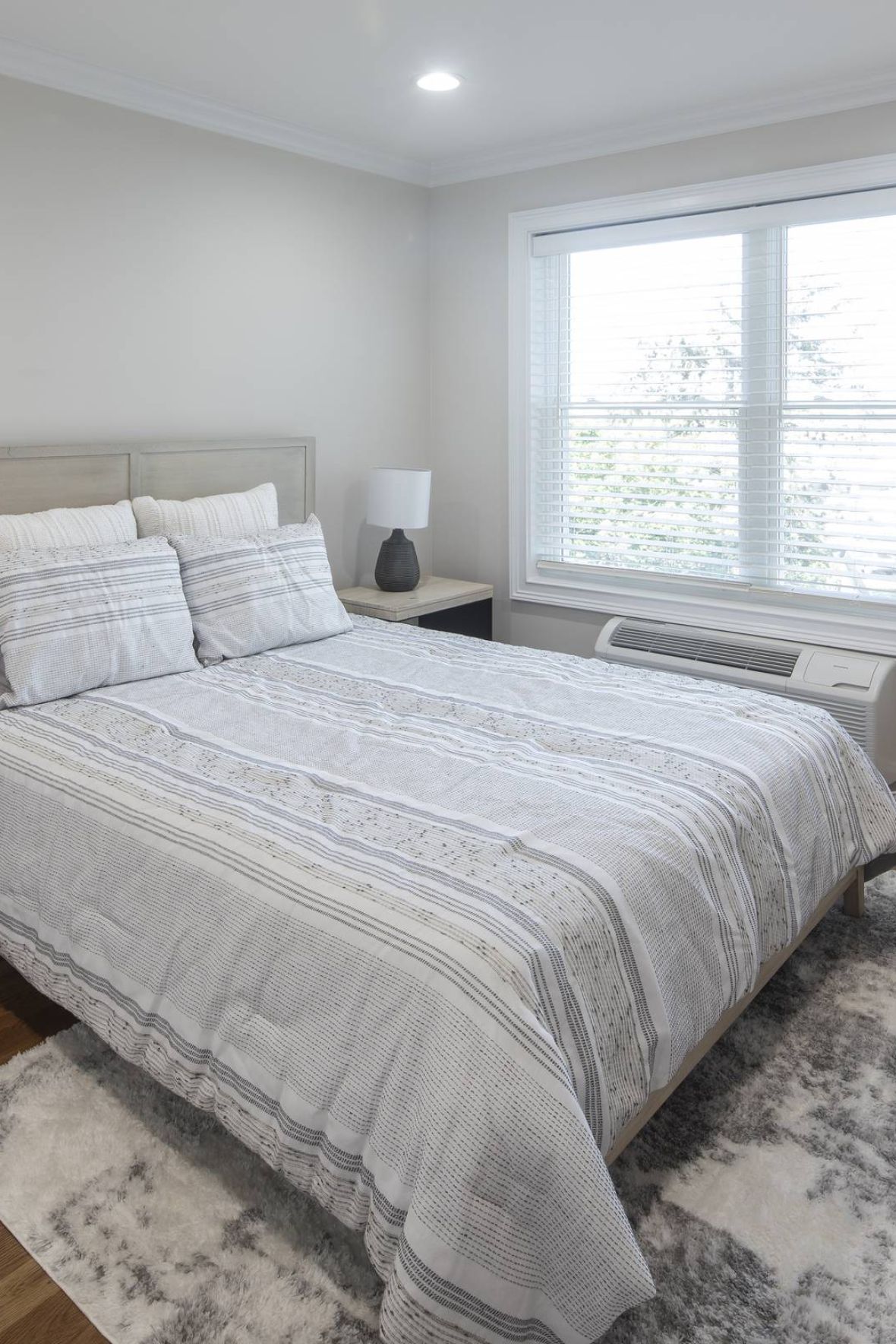 Legion Manormodern mid-century furnished bedroom with bed, side table, and round mirror