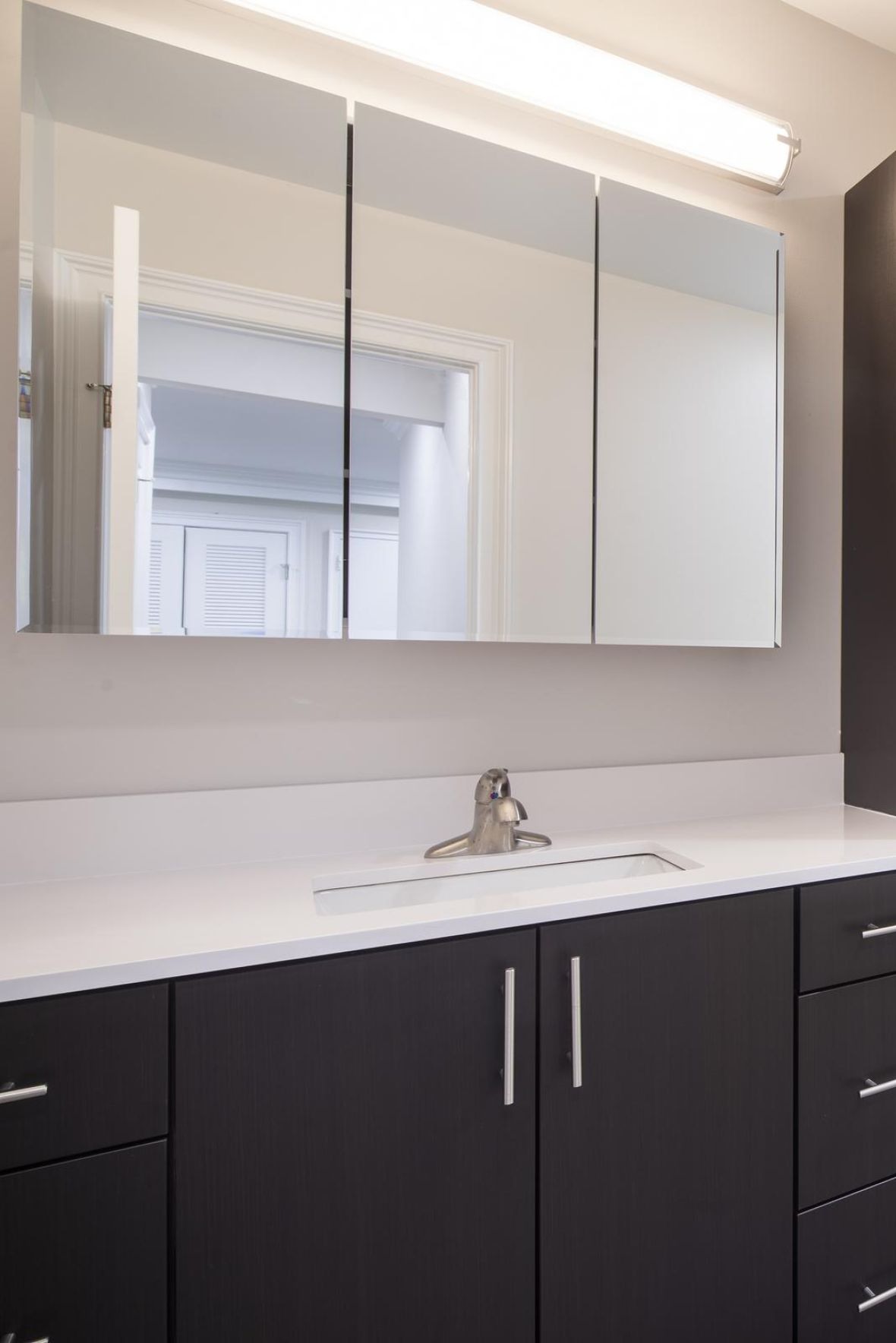 Leonia Manormodern mid-century furnished bedroom with bed, side table, and round mirror