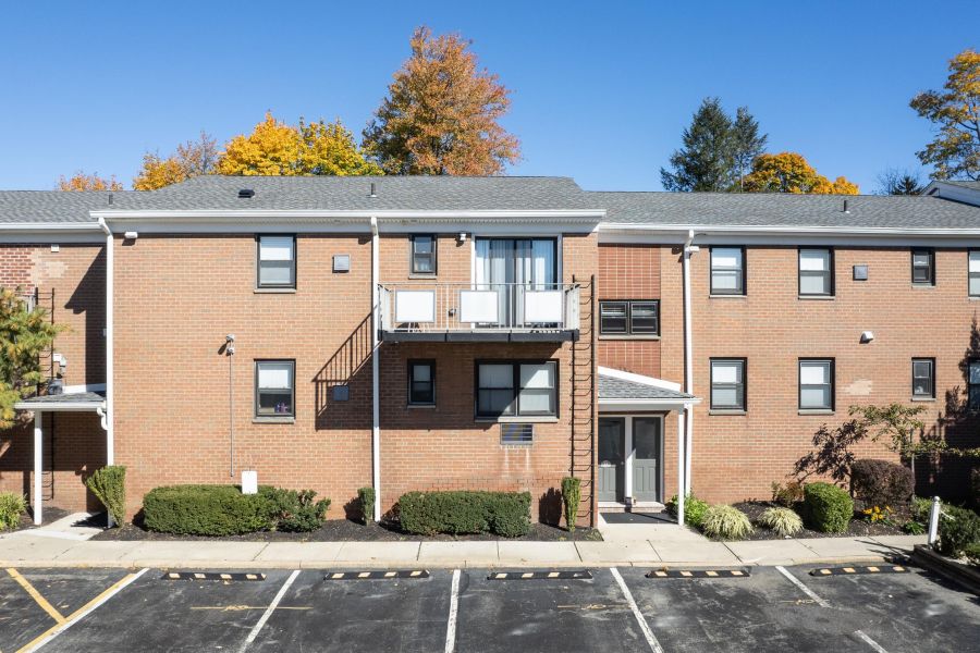 Linden Apartments Outdoor patio with wooden pergola, cushioned seating, throw pillows, and a round coffee table with drinks.