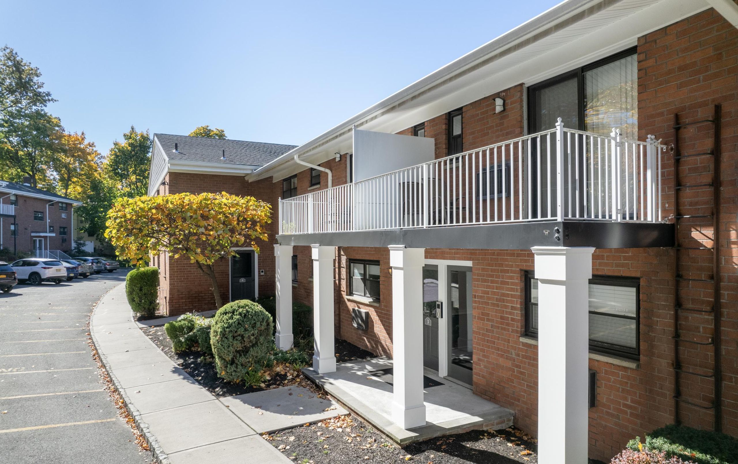Linden Apartments A modern apartment building with landscaped gardens and a wooden entrance canopy under a partly cloudy sky.