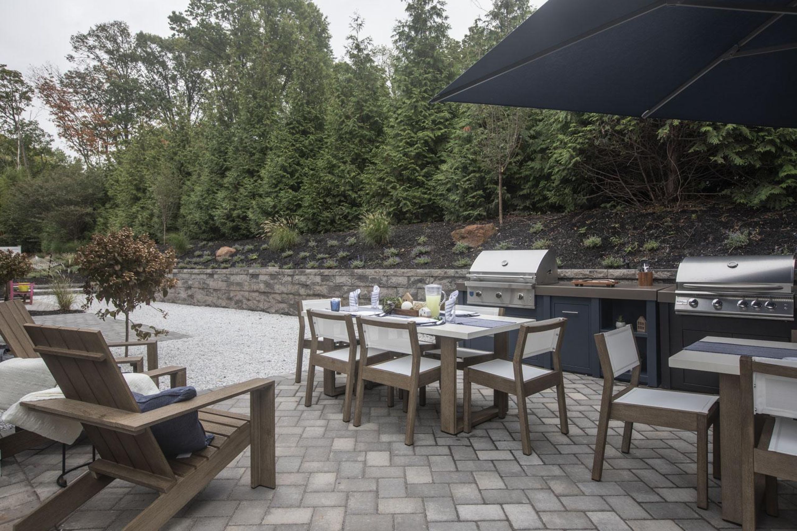 Linden ApartmentsPatio with wooden pergola, outdoor seating, chairs, and plants, overlooking a green lawn with flags.