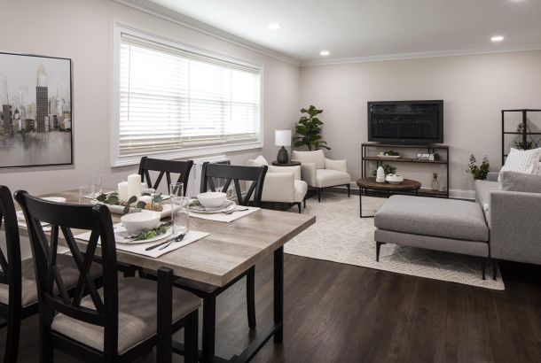 Modern open-concept dining and living room with neutral decor, dark wood floors, and ample natural light.