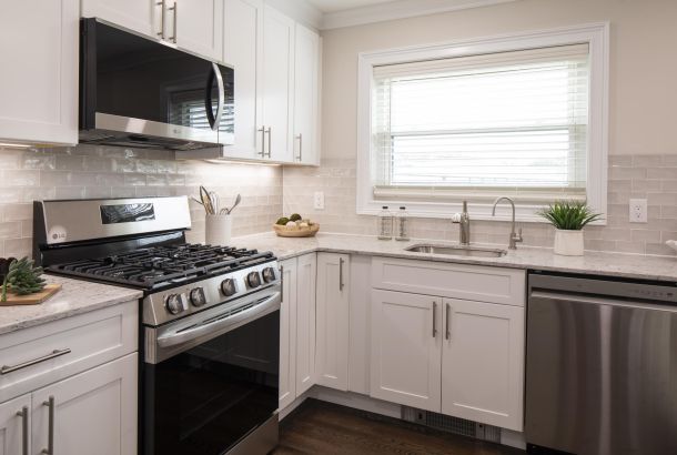 Modern kitchen with white cabinets, stainless steel appliances, and a window above the sink.