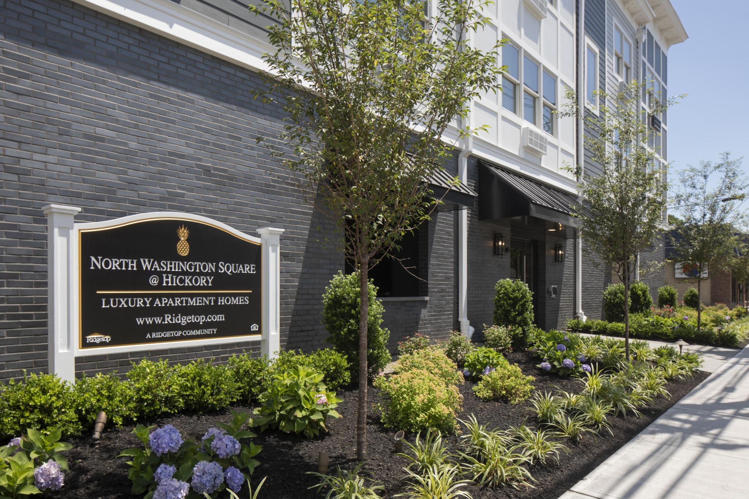Luxury apartment building entrance with landscaped garden and a sign reading "North Washington Square @ Hickory.