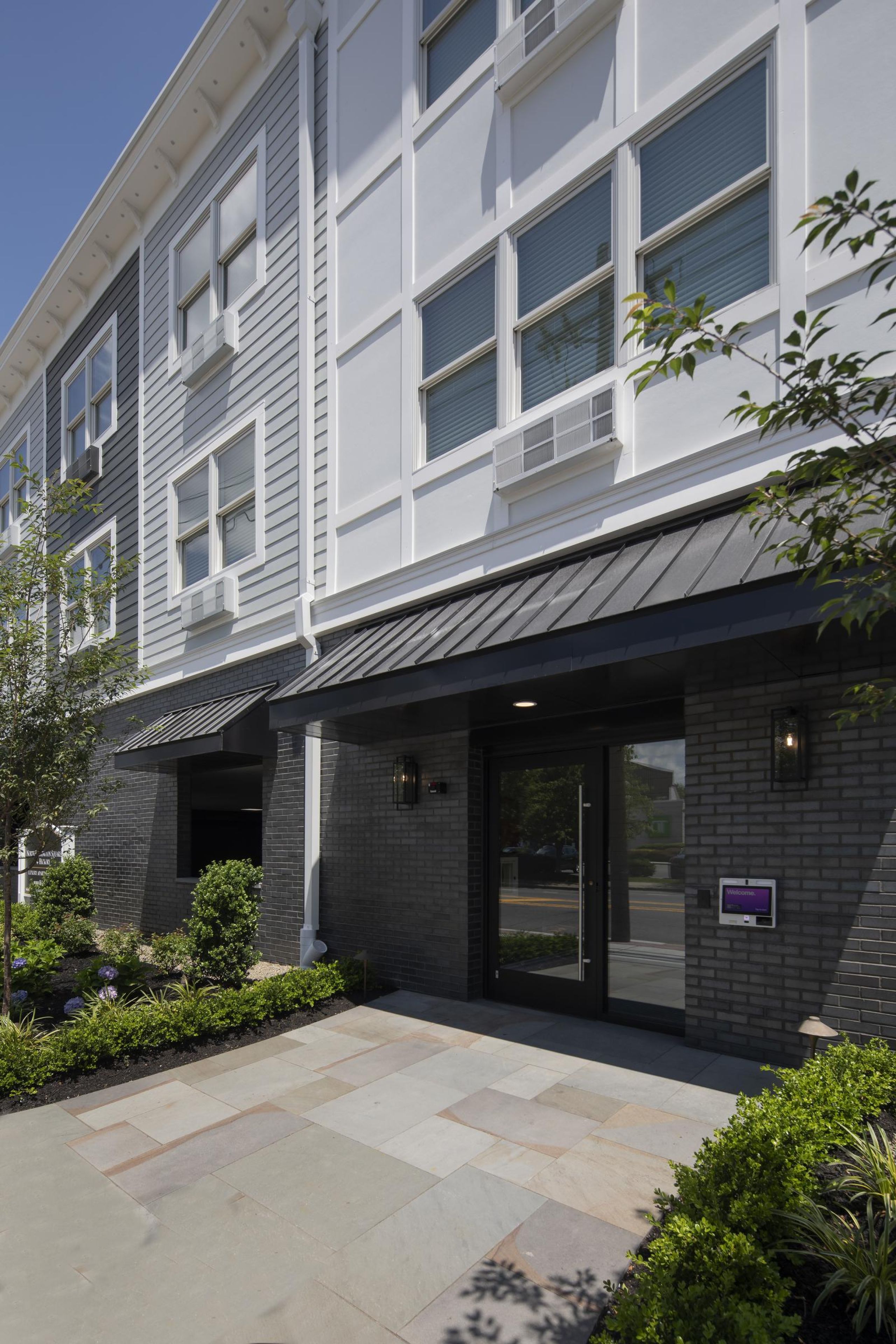 North Washington Square at Hickory A modern apartment building with landscaped gardens and a wooden entrance canopy under a partly cloudy sky.