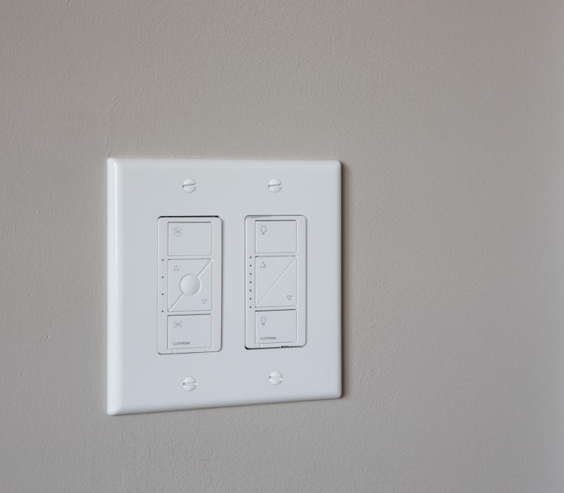 Two white modern light switches with slider controls on a beige wall.