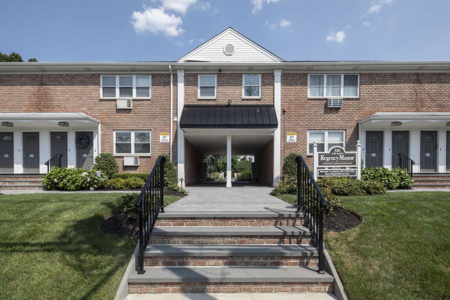 Regency Manor Checkers game in progress on a wooden table outdoors, with red and black pieces on a fabric board.