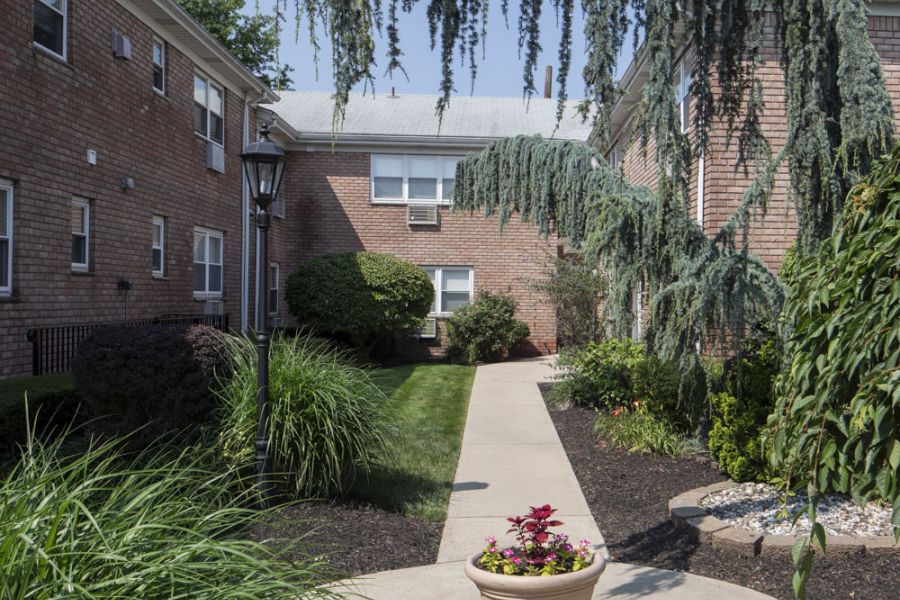 Regency Manor Checkers game in progress on a wooden table outdoors, with red and black pieces on a fabric board.