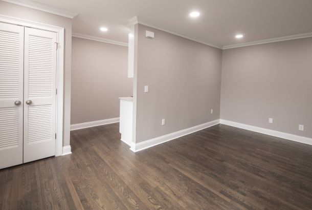 Empty room with hardwood floors, beige walls, white trim, and recessed ceiling lights. Closet doors on the left.