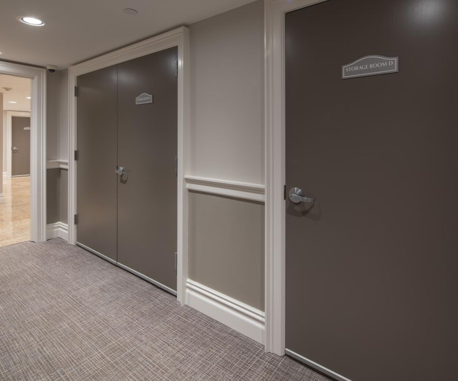 The Atrium A hallway with brown doors, one labeled "Storage Room," beige walls, and carpeted floor.