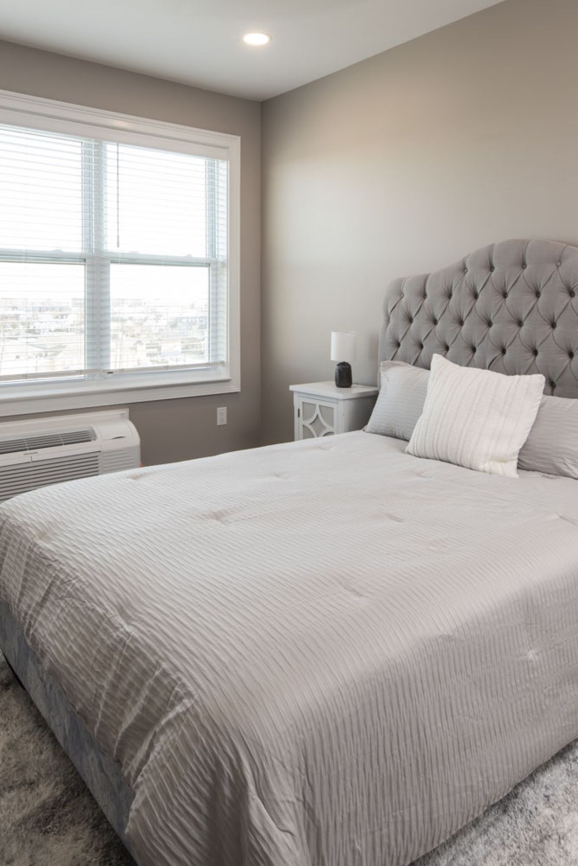 The Atriummodern mid-century furnished bedroom with bed, side table, and round mirror