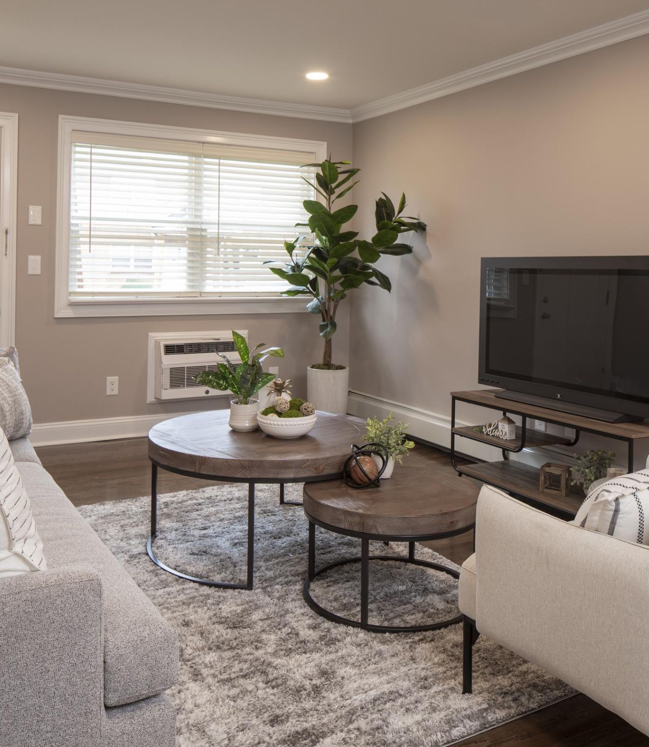 A cozy bedroom with a patterned bed, two lamps, wooden furniture, and a window letting in natural light.