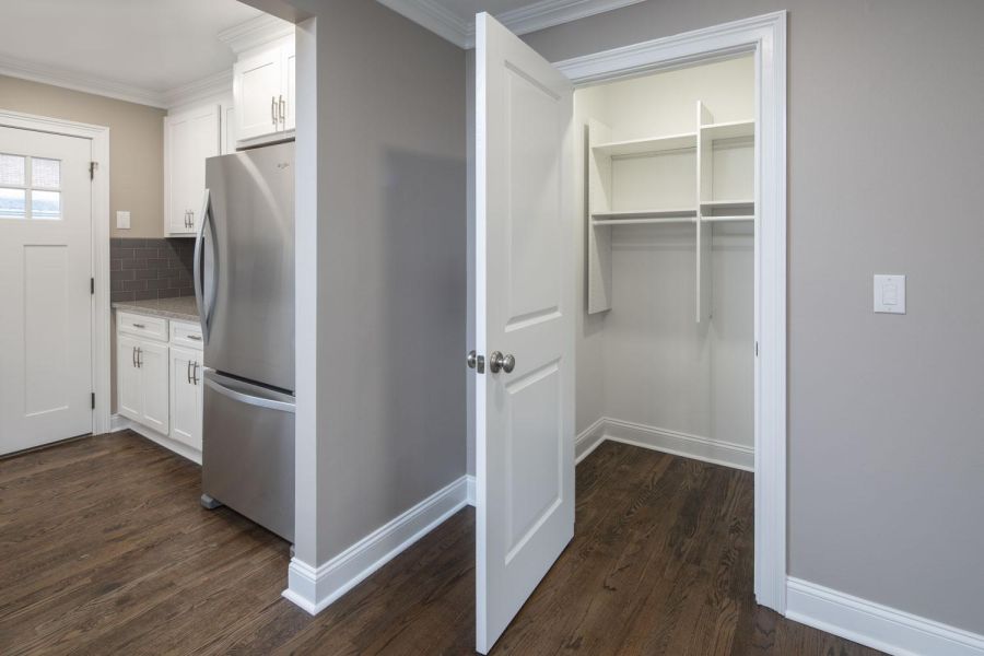 The Courtyard @ Clifton Open white door reveals an empty walk-in pantry next to a modern kitchen with stainless steel fridge.