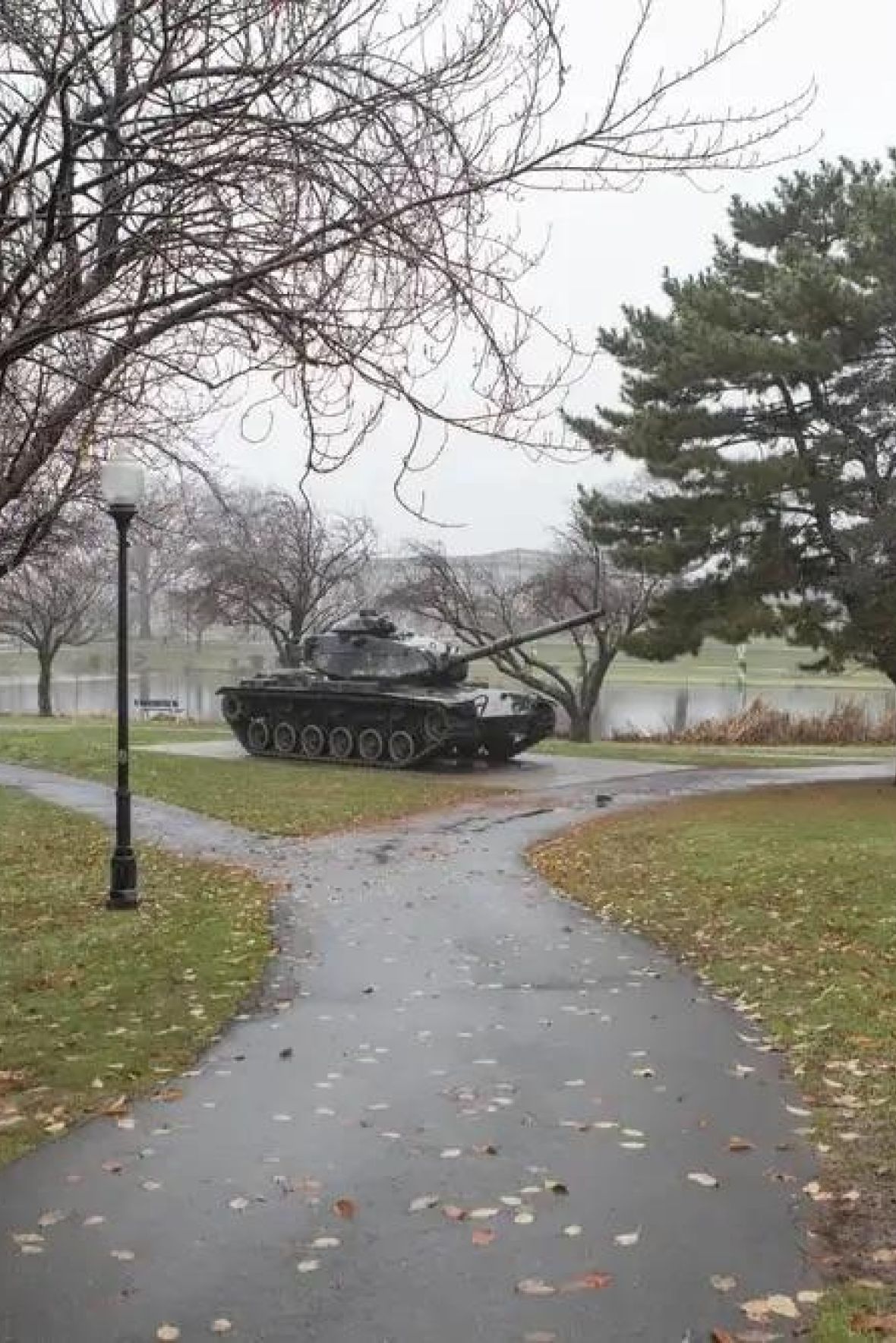 The Courtyard @ Clifton Empty outdoor tennis court with nets, surrounded by trees and buildings, under a partly cloudy sky.