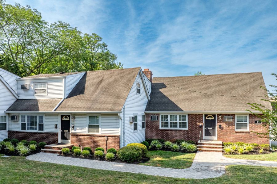 The East Hill A modern apartment building with landscaped gardens and a wooden entrance canopy under a partly cloudy sky.