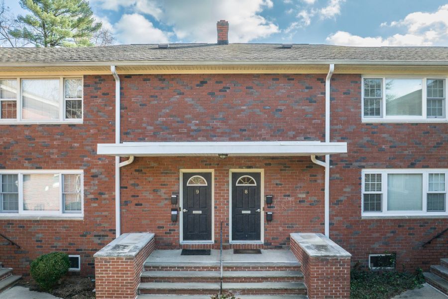The East Hill Two cream chairs and a wooden table with plants and decor against a modern, light wall.