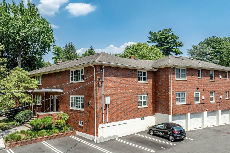 The East Hill Outdoor patio with wooden pergola, cushioned seating, throw pillows, and a round coffee table with drinks.