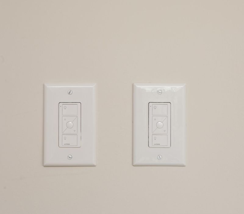 Two white light switches with multiple buttons mounted on a beige wall.