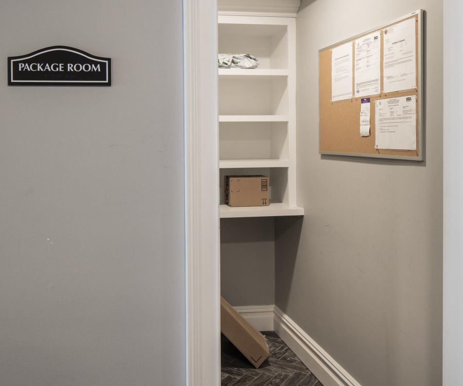 Small package room with shelves, a bulletin board, and packages on the floor and shelf.