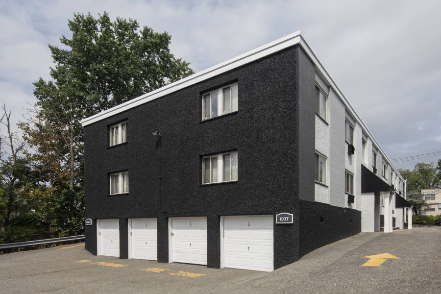 West Church Gardens A digital ButterflyMX intercom system is mounted on a white brick wall next to a wooden corner.