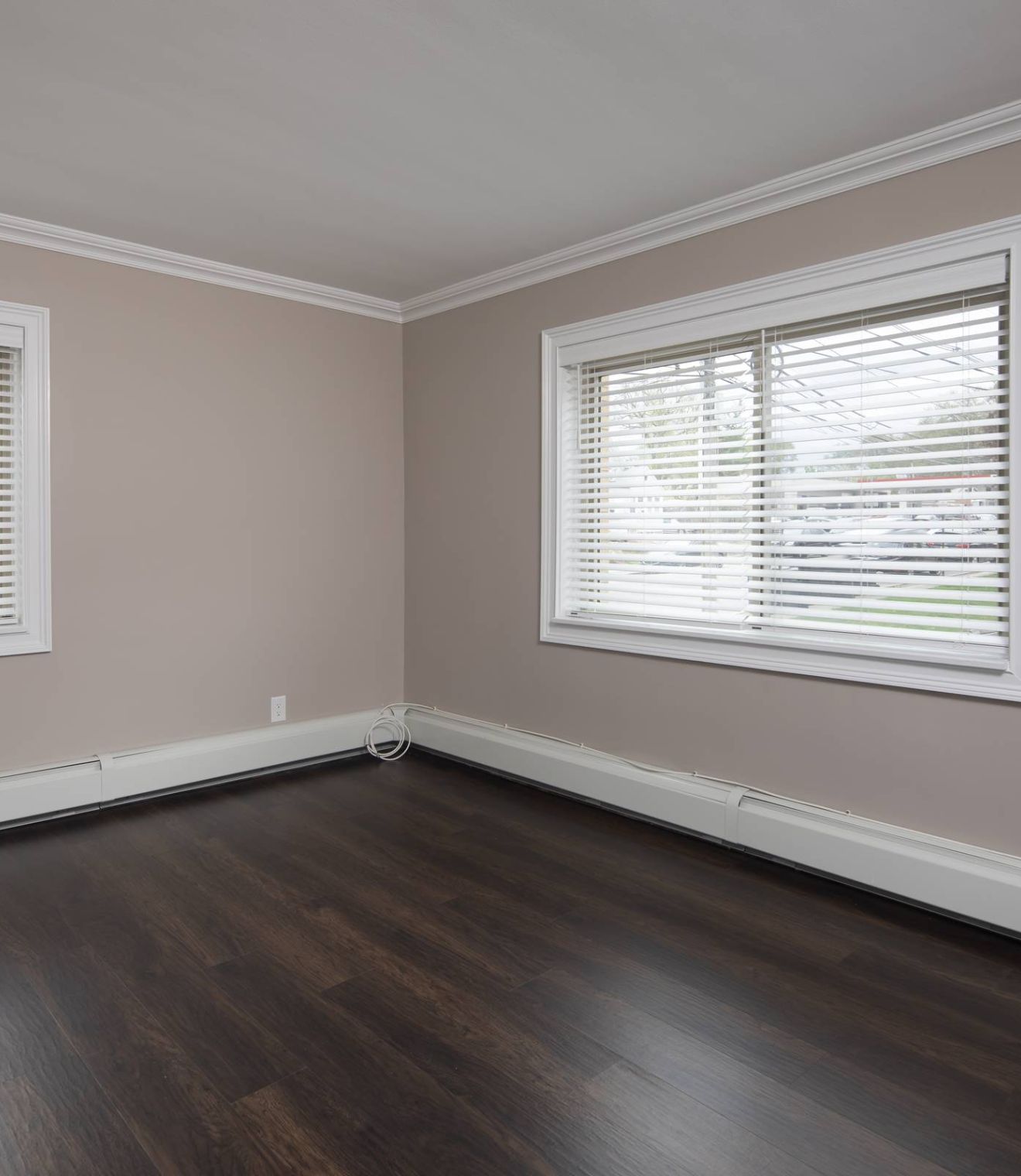 A bright bedroom with a neatly made bed, two bedside tables, lamps, and a window letting in natural light.