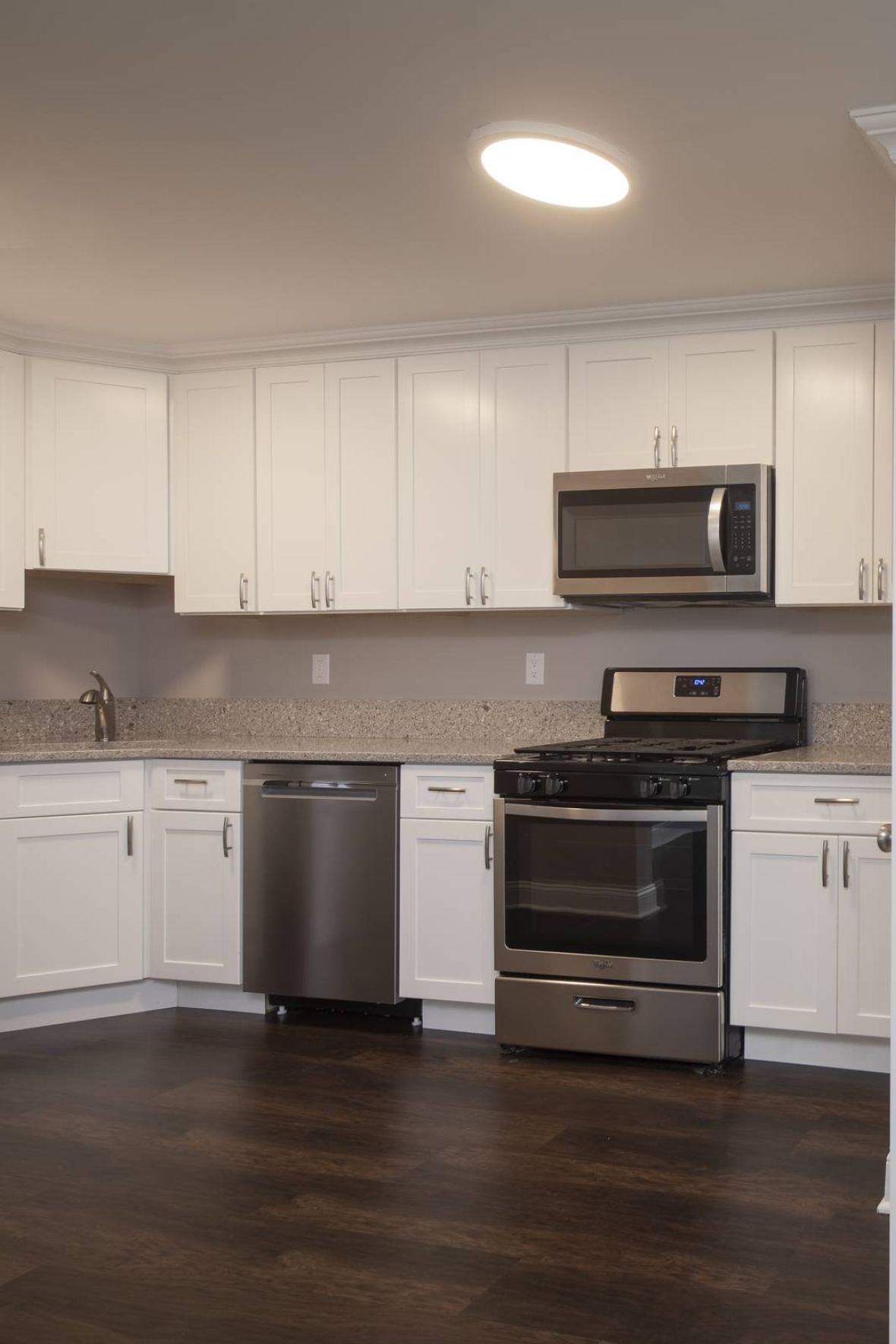 Modern kitchen with white cabinets and a closet containing a stacked washer and dryer unit.