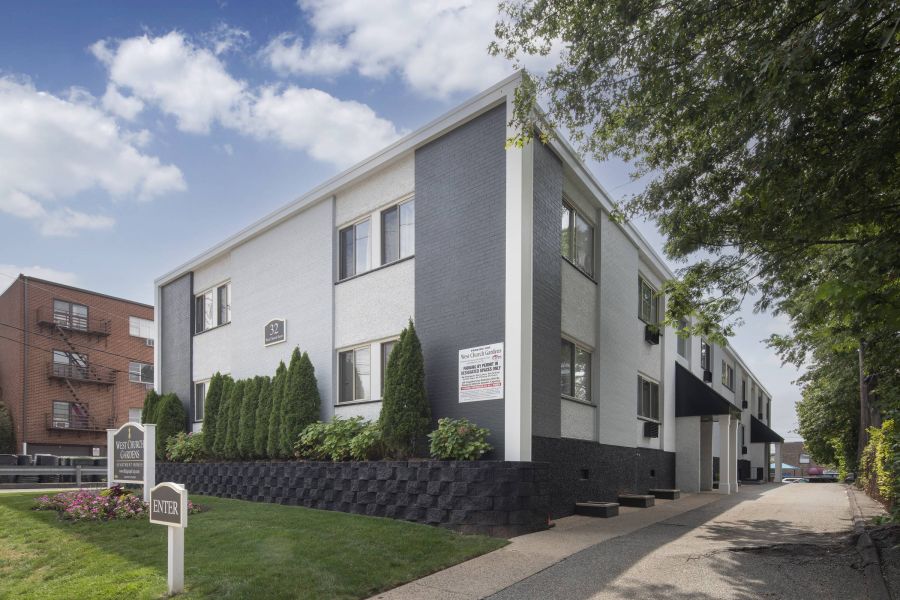 West Church Gardens Apartment building with black and white exterior, fire escapes, and garages on the ground floor.