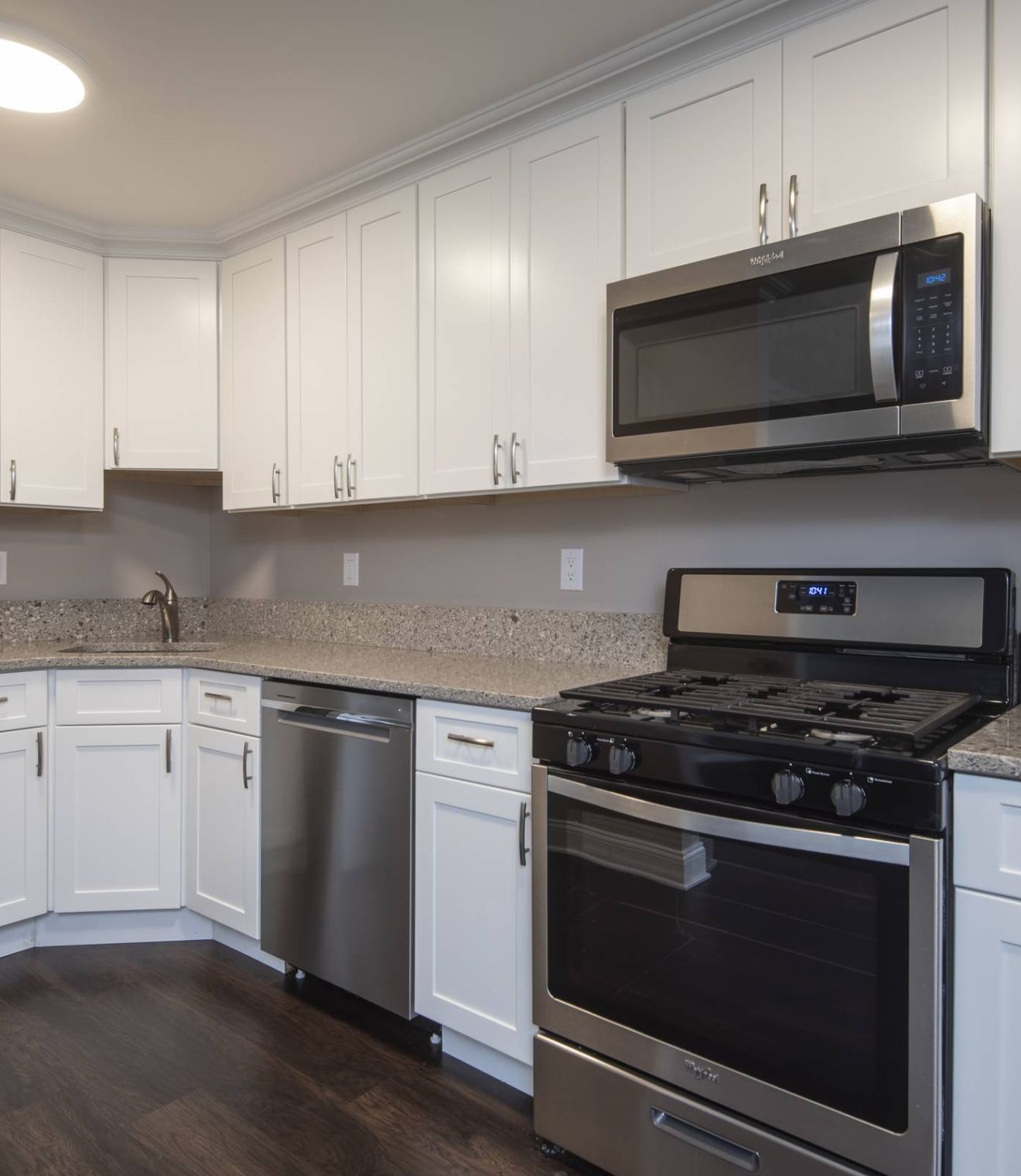 Modern kitchen with white cabinets, stainless steel appliances, and a marble island with three stools.