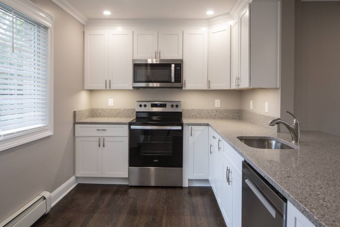 Modern kitchen with white cabinets, stainless steel appliances, and gray granite countertops.
