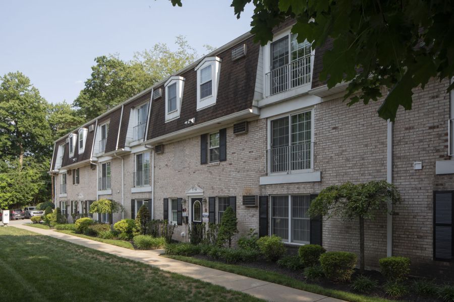 Westwood Manor A modern apartment building with landscaped gardens and a wooden entrance canopy under a partly cloudy sky.