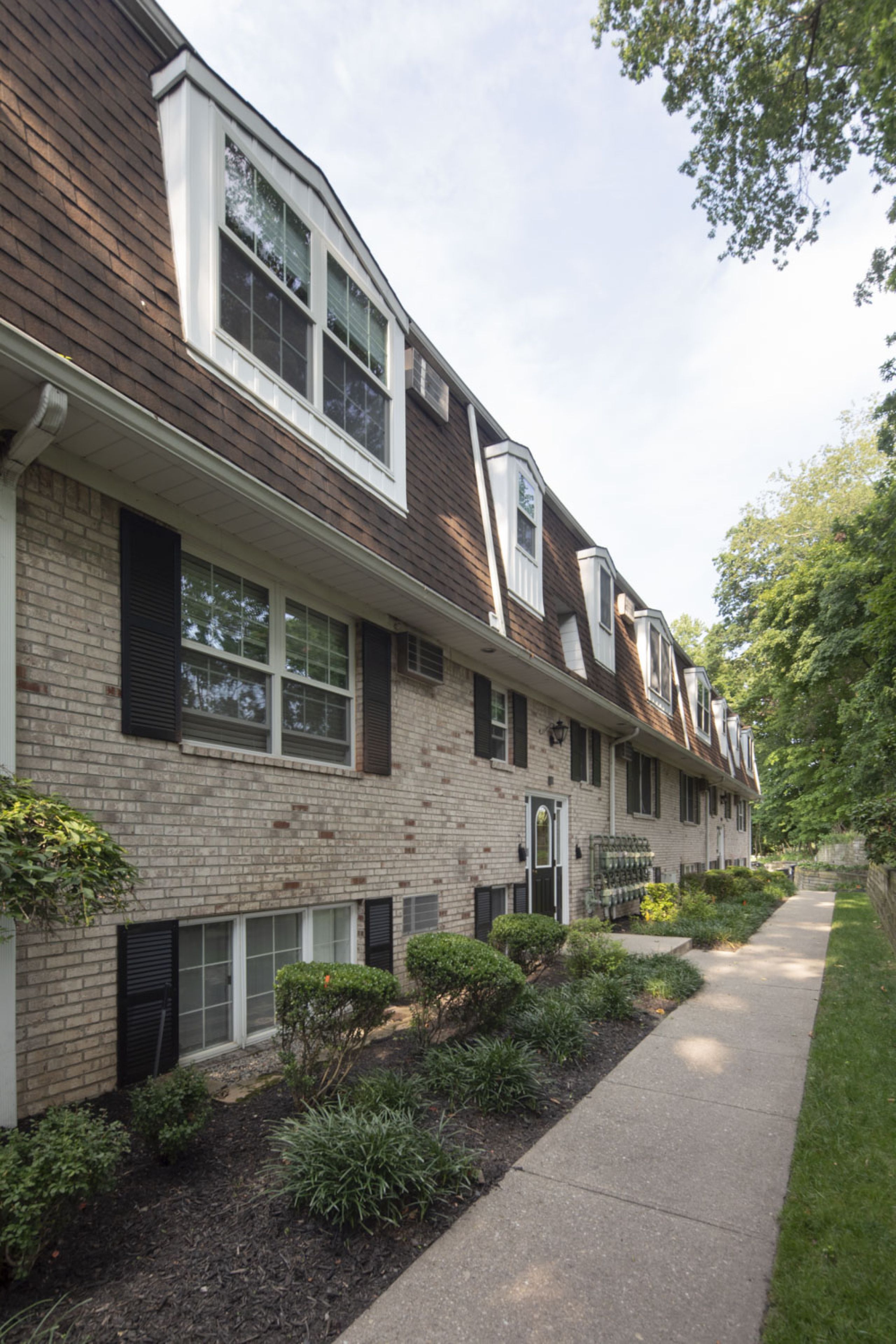 Westwood ManorPatio with wooden pergola, outdoor seating, chairs, and plants, overlooking a green lawn with flags.