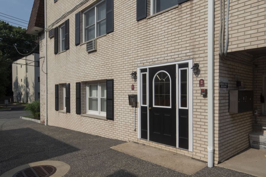 Westwood Manor Outdoor patio with wooden pergola, cushioned seating, throw pillows, and a round coffee table with drinks.