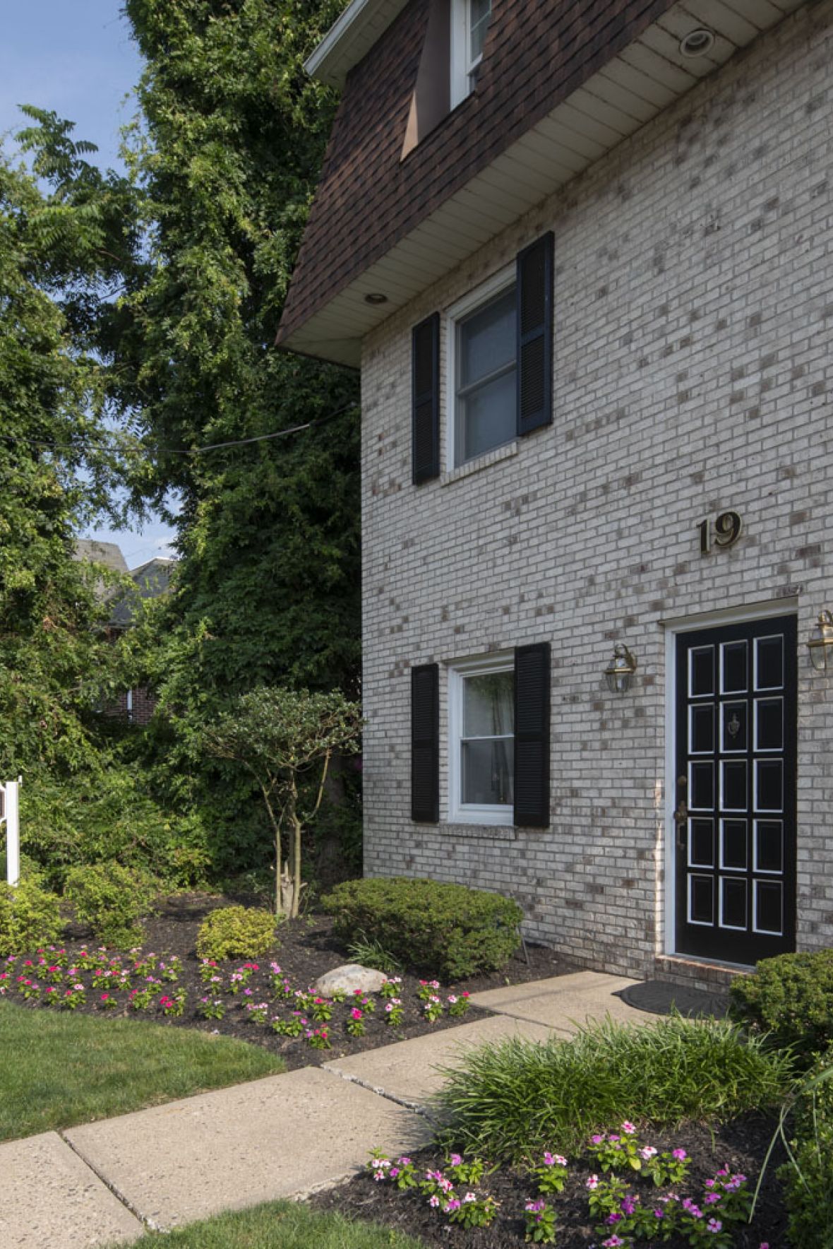 Westwood Manor A vintage clock stands in a plaza with blooming trees and a domed building in the background.