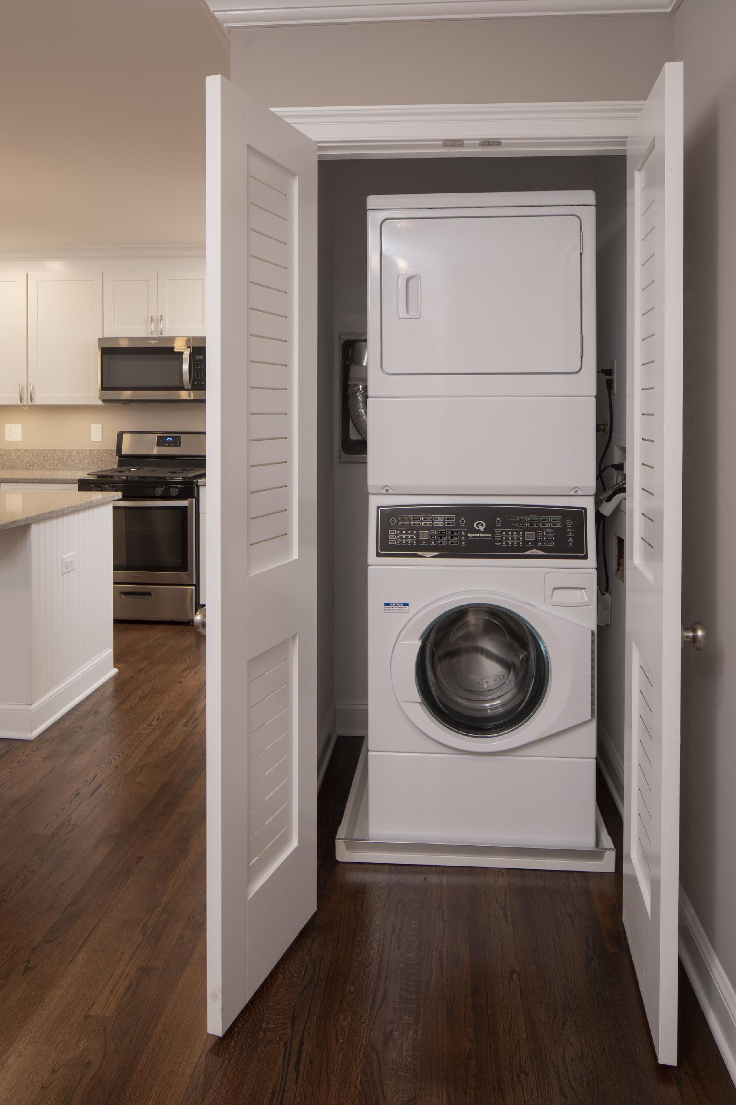 Woodland Hills Manor Two gray armchairs with pillows sit by a small table in a modern, gray-toned hallway near an elevator.