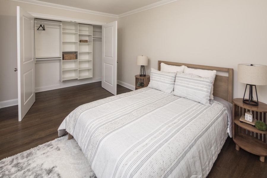 Ridgetop Neatly made bed in a bedroom with open closet, two lamps, and neutral-colored decor.