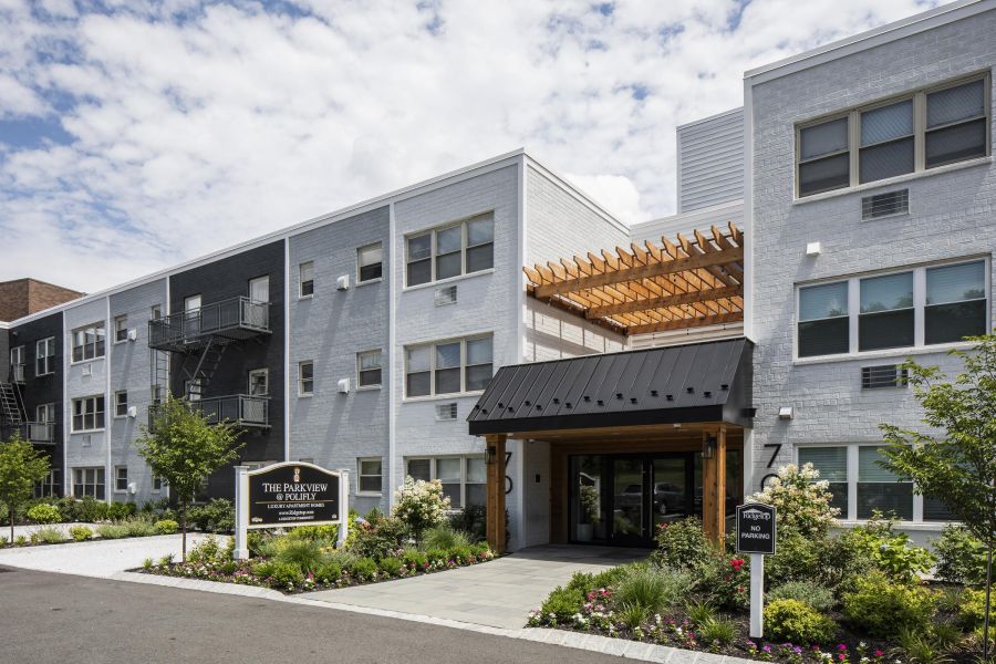 Ridgetop Modern three-story apartment building with a landscaped entrance and partly cloudy sky above.