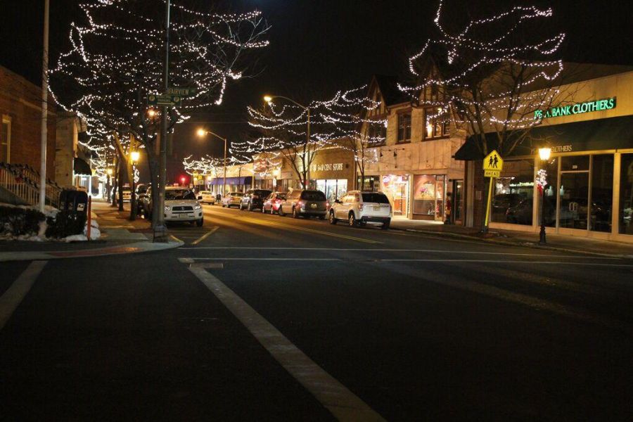 Downtown Westwood street at night with trees and storefronts decorated with white holiday string lights.