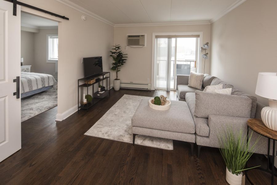 Ridgetop Modern living room with gray sectional sofa, TV, plants, and view into bedroom; natural light from patio doors.