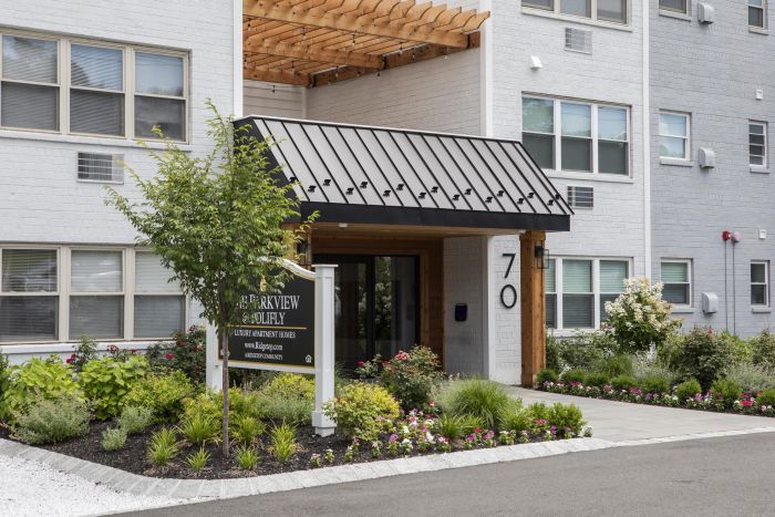 Entrance of a modern apartment building with landscaping and a sign reading "Parkview at Chelsey.