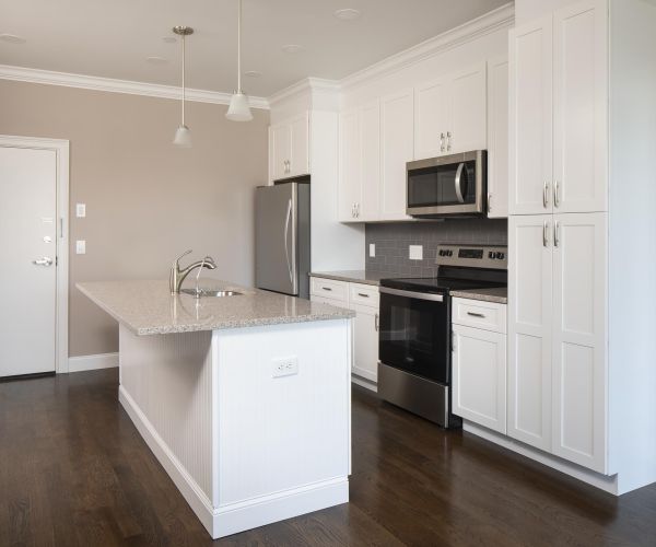 Modern kitchen on North Washington Square with white cabinets, stainless steel appliances, island, and Hickory dark wood floor.