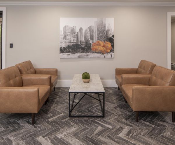 Two tan leather sofas face each other across a marble coffee table in the modern, neutral-toned living room of Legion Manor.