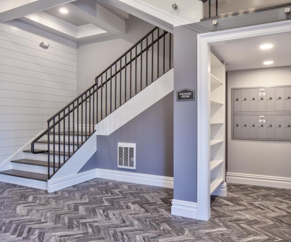 Modern entryway with a staircase, herringbone floor, and a mailroom with mailboxes on the right.